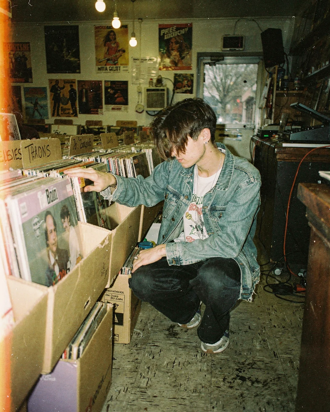 Record shop browsing scene in disposable-camera style, representing shopper evaluation signals and try-on data for merchandising decisions