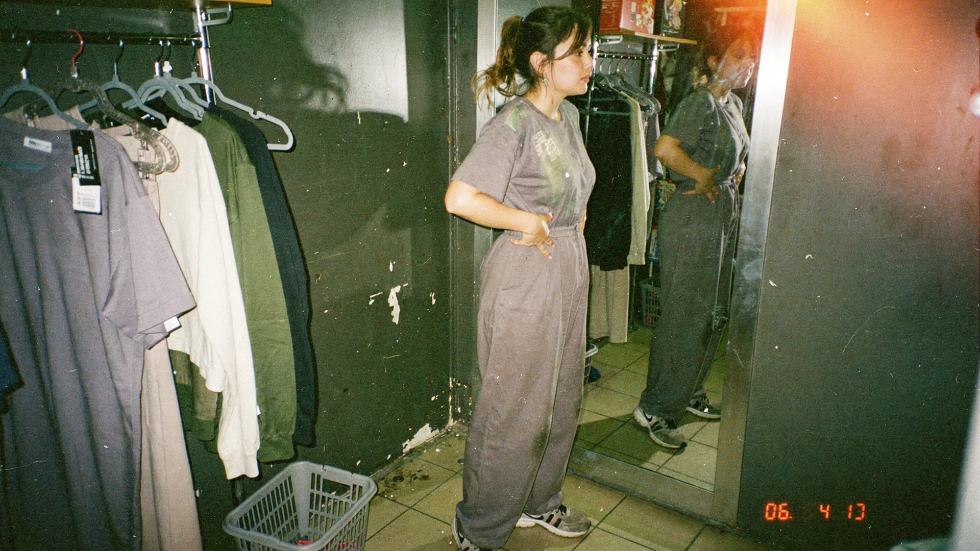 Fitting room mirror with shopper evaluating wide-leg jumpsuit silhouette and proportion